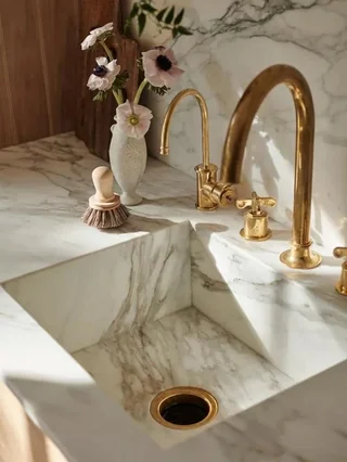 Marble integrated sink with smooth veining, paired with a sleek gold faucet.